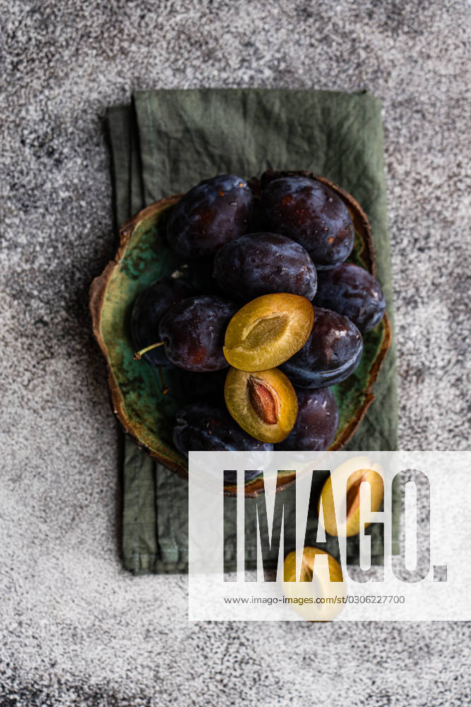 IMAGO Creative, Jahreszeit Sommer, Food, Pflaume Top view of organic ripe plums served in marble bowl placed on napkin on gray surface Model Released AnnaBogush_ID16675_508696_002