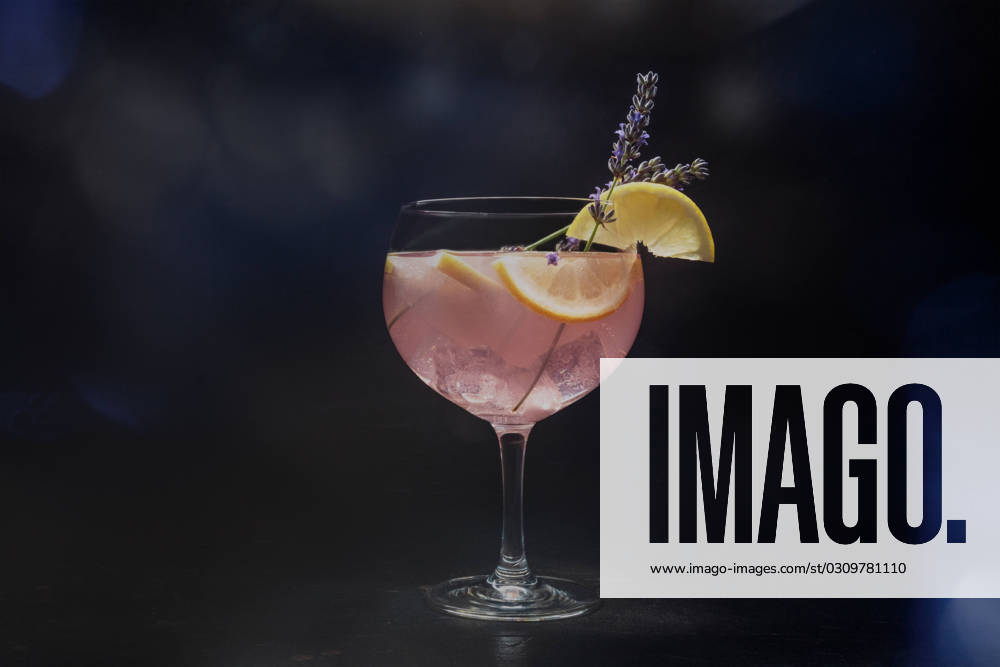 Fancy cocktail with fresh fruit. Gin and tonic drink with ice at a party Fancy cocktail with fresh fruit. Gin and tonic drink with ice at a party, on a black background. Alcohol with lavender and lemon, toned image