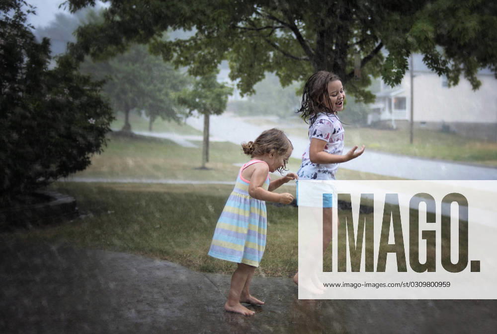 Sisters jumping in puddles during summer rain Wooster, Ohio, United States CR_JOKU231022-1268193-01 ,model released, Symbolfoto