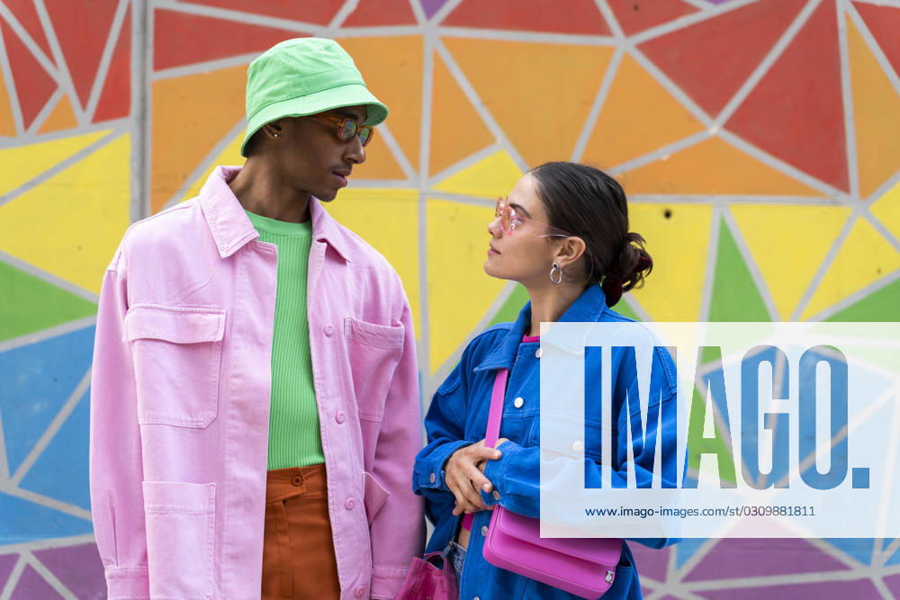 Multiracial couple talking in front of colorful wall model released, Symbolfoto, AFVF09324