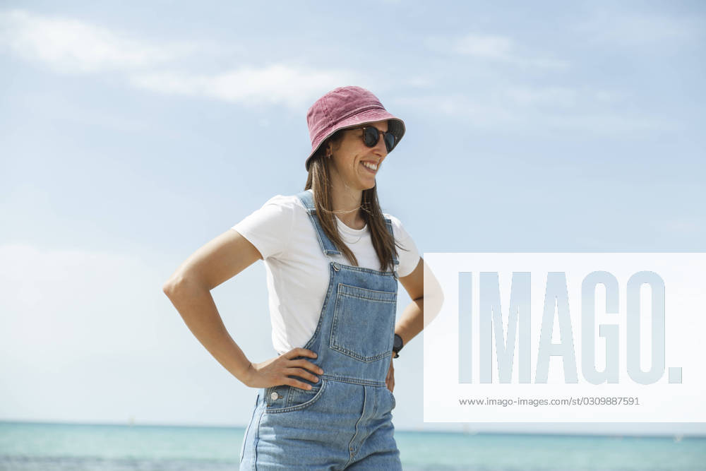 Smiling woman with arms akimbo standing near sea under sky model released, Symbolfoto, PCLF00663