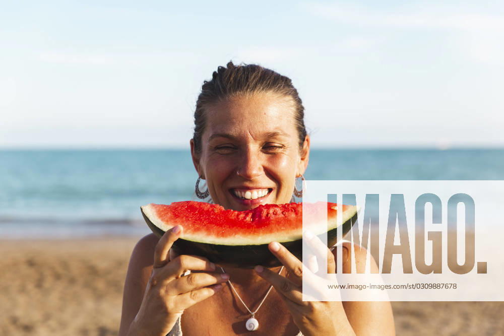 Happy woman enjoying watermelon at beach model released, Symbolfoto, PCLF00715