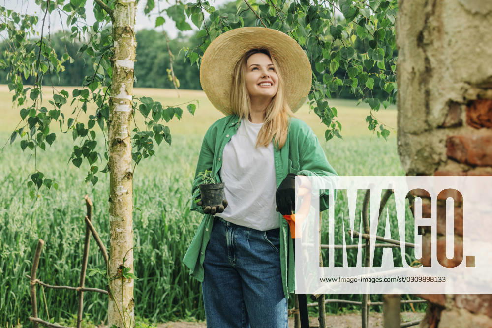 Smiling woman holding potted plant in garden model released, Symbolfoto, VSNF01129
