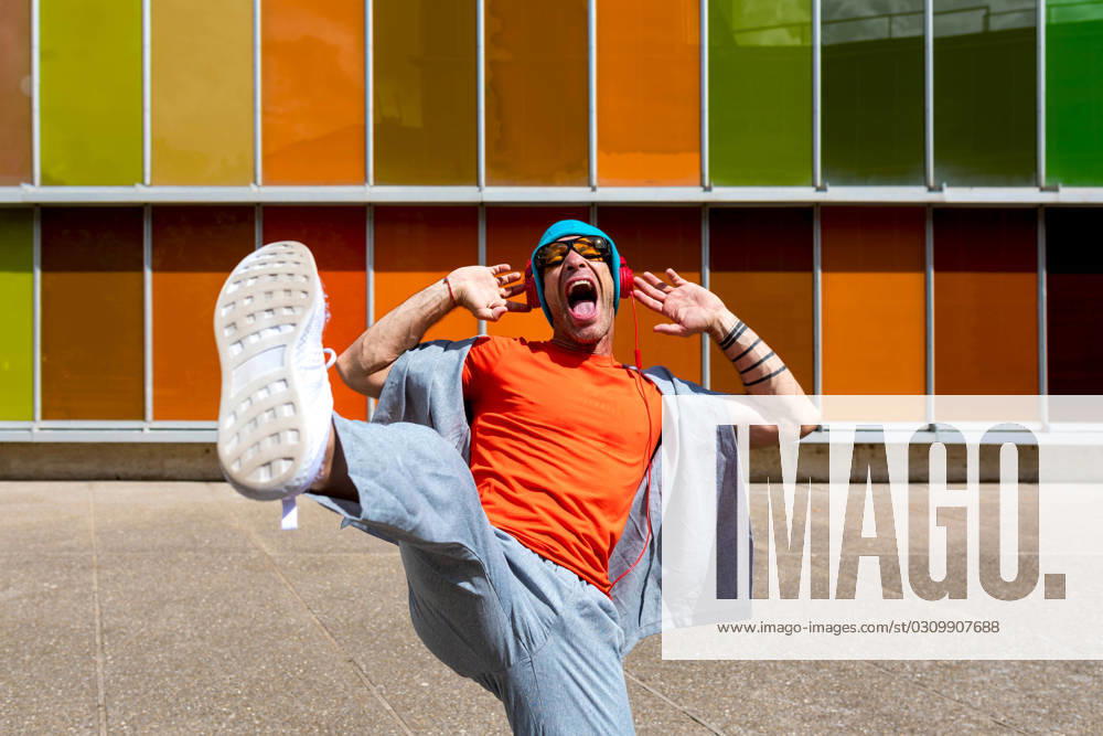 Joyful man dancing energetically in front of a multicolored windowed building Model Released SergioVictorVega_ID16857_514943_015