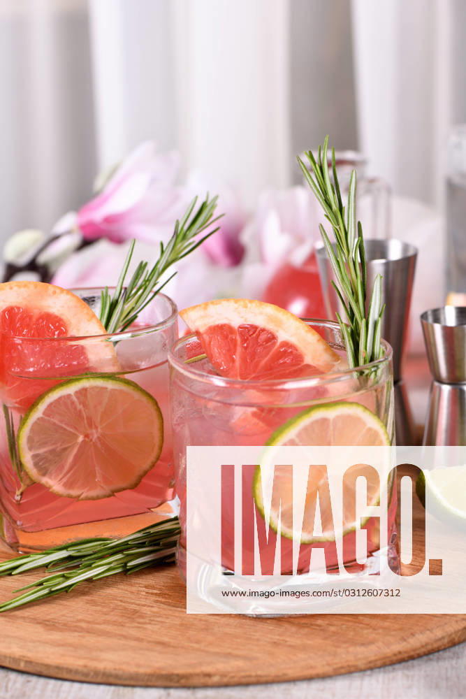 Pink Paloma cocktail red grapefruit with tonic Refreshing organic cocktail with grapefruit slice, lime and rosemary sprig in a glass