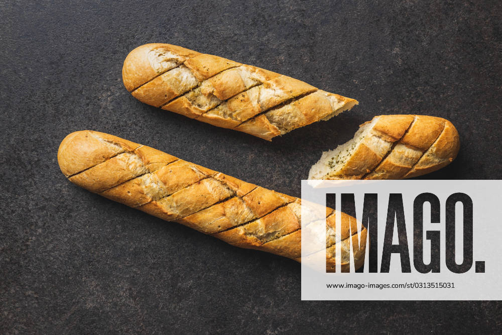 Roasted baguette with garlic butter. Crunchy sliced garlic bread on black table. Roasted baguette with garlic butter. Crunchy sliced garlic bread on black table. Top view.