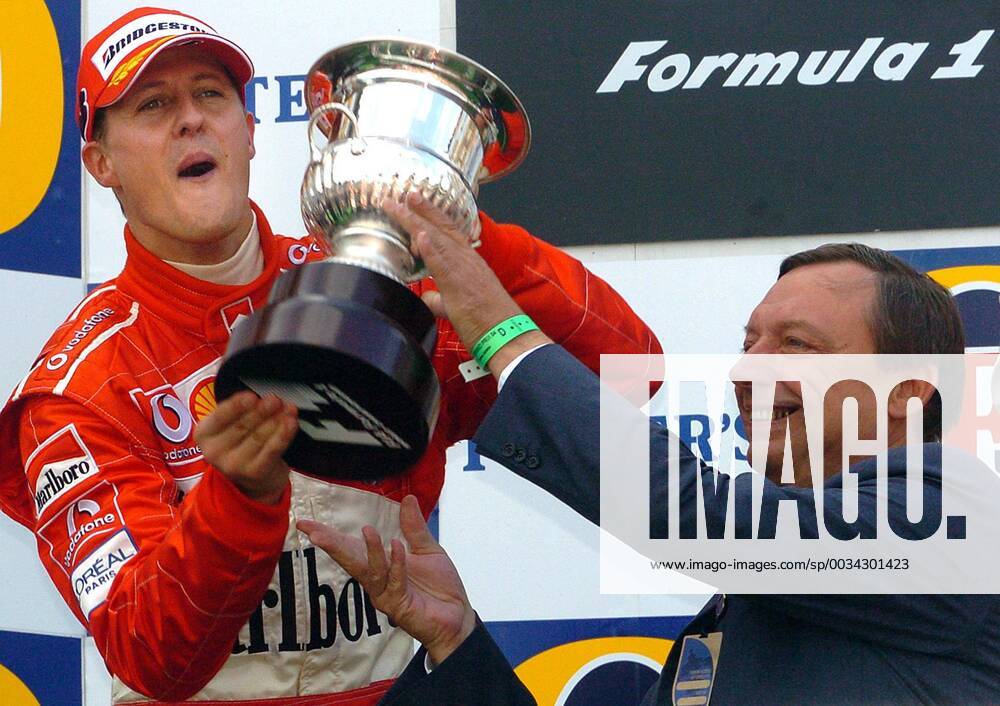 BRU443 - - FRANCORCHAMPS, BELGIUM : German Michael Schumacher celebrates as he receives his trophy from the hands of Walloon Minister of Economy Michel Daerden (R) on the podium of the Belgian Formula One Grand Prix, Sunday 29 August 2004, on the race track of Spa-Francorchamps. Finnish Kimi Raikkonen won the race and Michael Schumacher got World Champion for the 7th time. BENOITxDOPPAGNE x2141181x