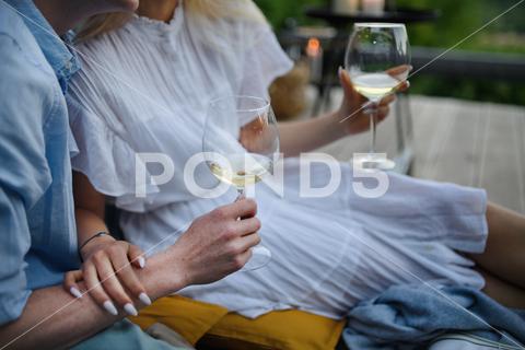 A young couple clinking with wine outdoors, weekend away in tiny house in countryside, sustainable living. Close-up. close-up, love, wine, couple, woman, man, outdoor, happy, terrace, romance, romantic, together, young, drink, glass, person, smiling, caucasian, celebration, lifestyle, garden, party, relationship, two, alcohol, cheerful, vacation, tourism, closeness, date, honeymoon, newlyweds, lover, positive, togetherness, drinking, champagne, evening, holding, tiny house, holiday, nature, off beat, relax, meditation, digital detox, candle, hygge, travel