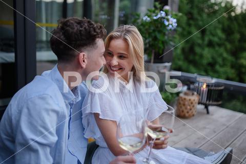 A young couple clinking with wine outdoors, weekend away in tiny house in countryside, sustainable living. love, wine, couple, woman, man, outdoor, happy, terrace, romance, romantic, together, young, drink, glass, person, smiling, caucasian, celebration, lifestyle, garden, party, relationship, two, alcohol, cheerful, vacation, tourism, closeness, date, honeymoon, newlyweds, lover, positive, togetherness, drinking, champagne, evening, holding, tiny house, holiday, nature, off beat, relax, meditation, digital detox, candle, hygge, travel, weekend away