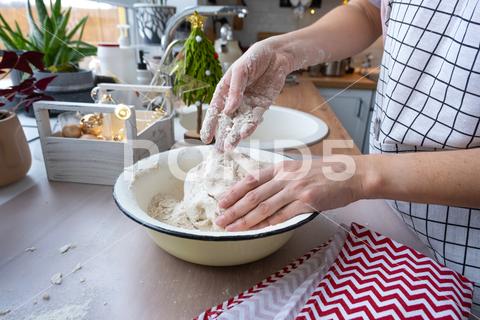 Hands knead thick dough on the kitchen table, decorated with festive decorations for Christmas and New year. Baking at home, aroma and comfort. Close-up knead, thick, dough, kitchen, table, Christmas, New year, Baking, home, aroma, comfort, Close up, Hands, flour, cookies, housewife, pizza, wheat, bread, mood, cozy, interior, decor, preparing, sculpt, woman, cook, lifestyle, dessert, cutting, form, prepare, knead, making, shape, raw, baker, recipe, kneading, cooking, pastry, sweet, winter, holiday, cookie, bake, preparation, bakery, homemade, food