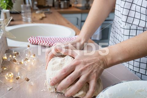 Hands knead thick dough on the kitchen table, decorated with festive decorations for Christmas and New year. Baking at home, aroma and comfort. Close-up knead, thick, dough, kitchen, table, Christmas, New year, Baking, home, aroma, comfort, Close up, Hands, flour, cookies, housewife, pizza, wheat, bread, mood, cozy, interior, decor, preparing, sculpt, woman, cook, lifestyle, dessert, cutting, form, prepare, knead, making, shape, raw, baker, recipe, kneading, cooking, pastry, sweet, winter, holiday, cookie, bake, preparation, bakery, homemade, food