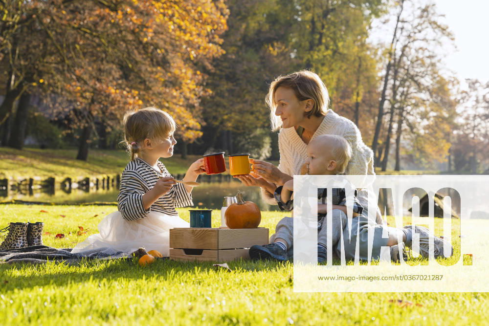 Smiling mother toasting cup with daughter near lake on sunny day model released, Symbolfoto, NDEF01360