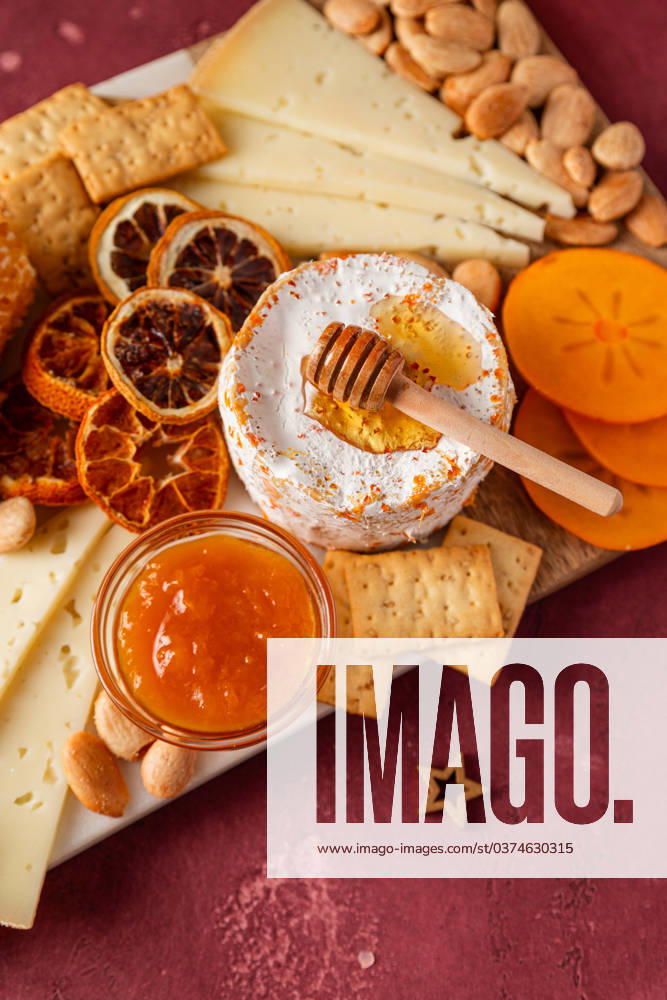 Gourmet cheese platter with honey, dried fruit, and nuts on a rustic table. Model Released CintiaViudez_ID18056_543210_006