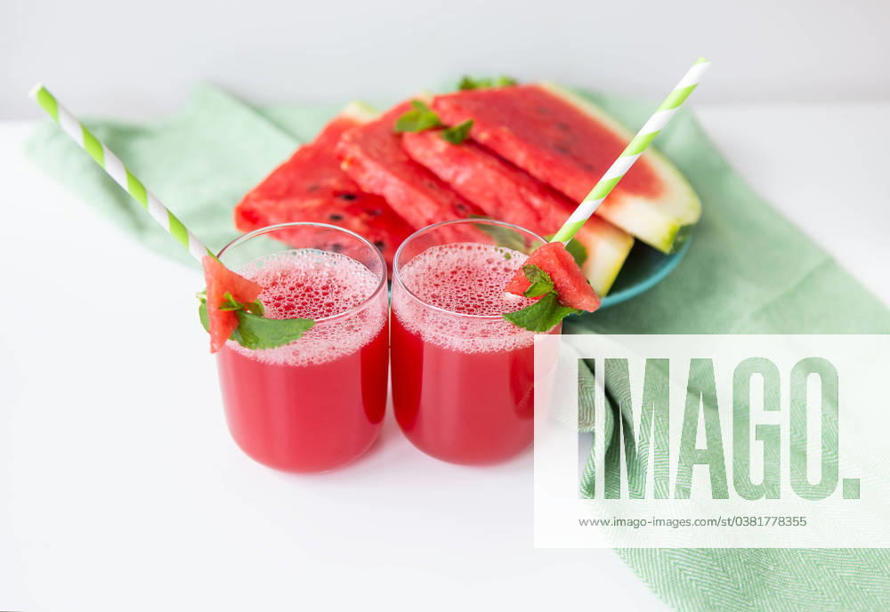 Juicy freshly squeezed watermelon juice in a glass along with a green tube, against a green napkin. Juicy freshly squeezed watermelon juice in a glass along with a green tube, against a green napkin