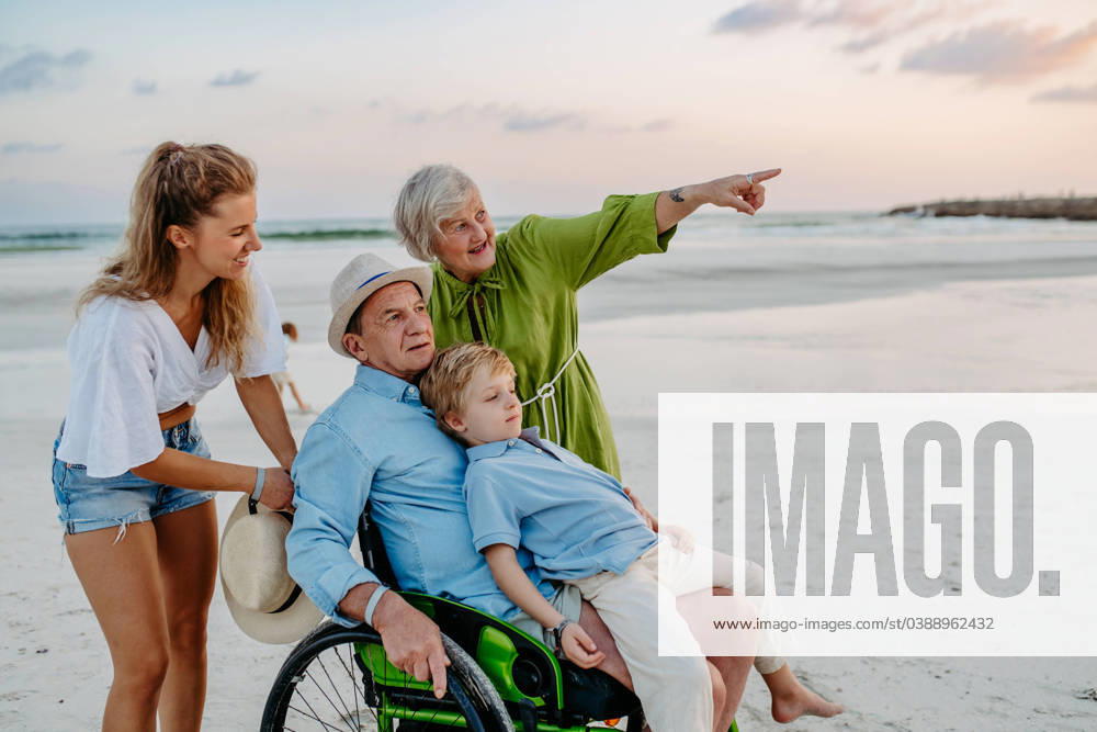 Little boy with his mother and granfather on wheelchair, having fun and enjoying sea together. Little boy with his granfather on wheelchair, having fun and enjoying sea. model released