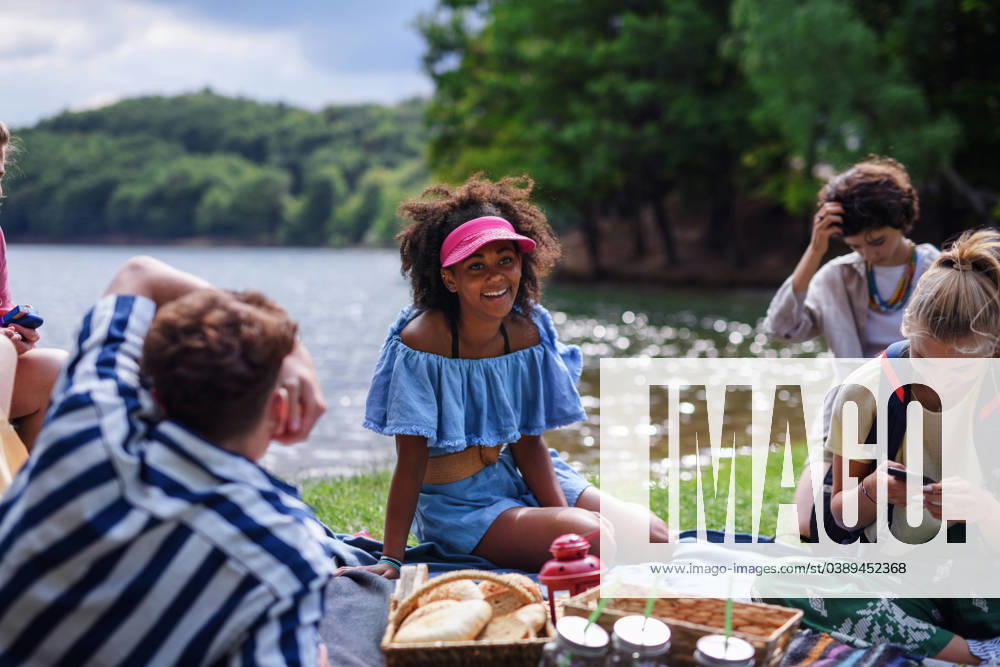 Group of multiracial young friends camping near lake and and having barbecue together. A group of multiracial young friends camping near lake and and having barbecue together. model released