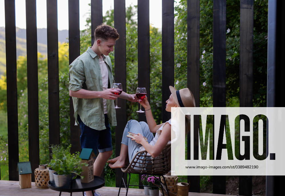 Young couple clinking with wine outdoors, weekend away in tiny house in countryside, sustainable living. A young couple clinking with wine outdoors, weekend away in tiny house in countryside, sustainable living. model released