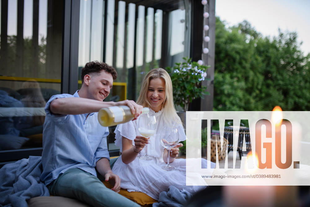 Young couple clinking with wine outdoors, weekend away in tiny house in countryside, sustainable living. A young couple clinking with wine outdoors, weekend away in tiny house in countryside, sustainable living. model released