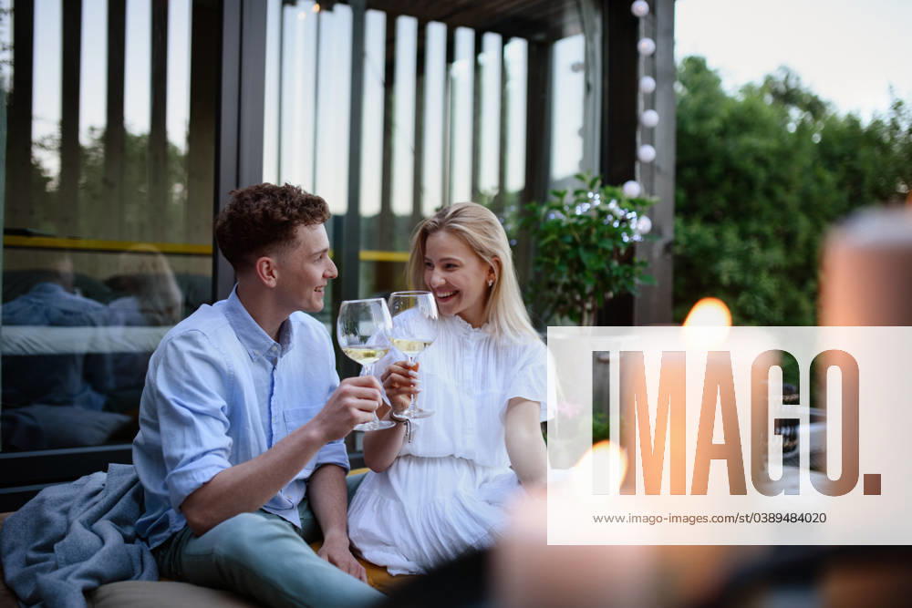 Young couple clinking with wine outdoors, weekend away in tiny house in countryside, sustainable living. A young couple clinking with wine outdoors, weekend away in tiny house in countryside, sustainable living. model released