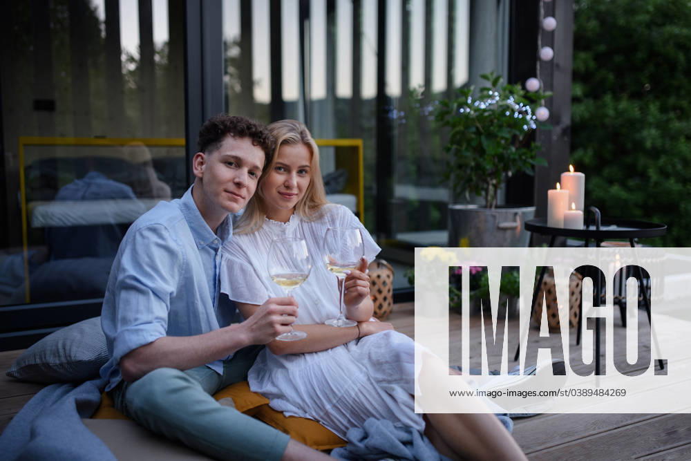 Young couple clinking with wine outdoors, weekend away in tiny house in countryside, sustainable living. A young couple clinking with wine outdoors, weekend away in tiny house in countryside, sustainable living. model released