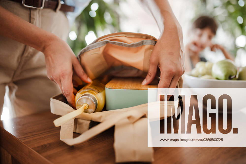 IMAGO Creative, Food, Trend, Meal Prep Mother packing school bag for kid. Putting bottle of juice, snacks for children into school bag. Snack, school lunch in a snack box for school. Mother packing school bag for kid. Putting bottle of juice, snacks for her children into school bag. Snack, school lunch in a snack box for school. model released
