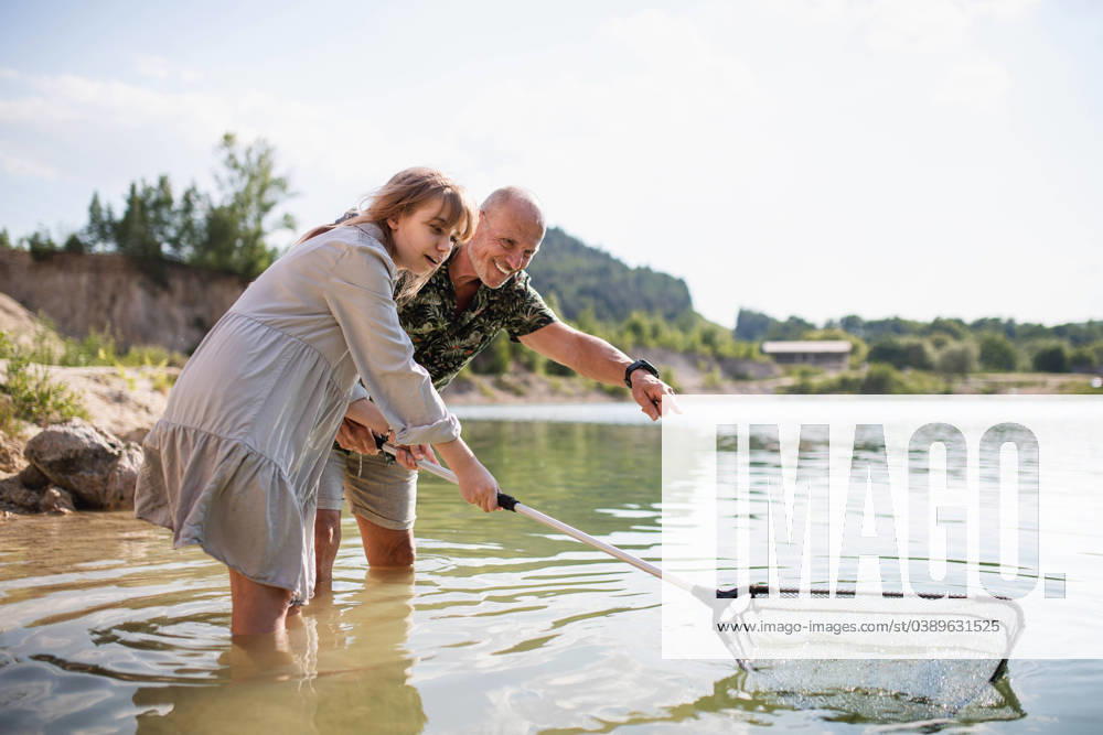 Happy preteen girl and grandfather with fishing net on summer holiday by lake. Happy preteen girl and senior grandfather with fishing net on summer holiday by lake. model released