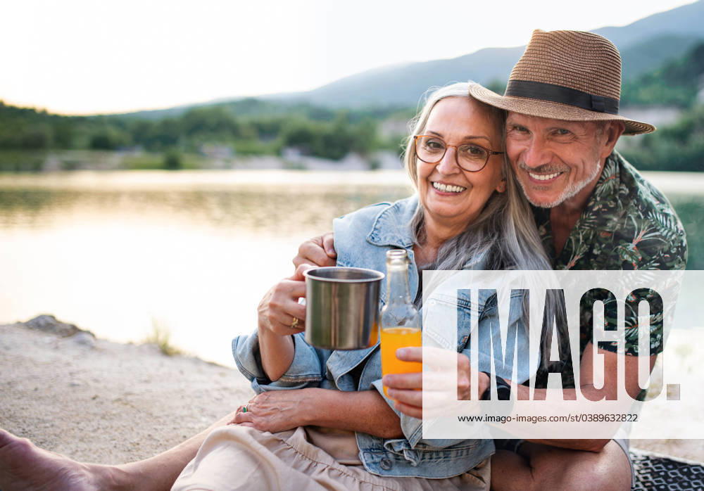 Happy senior couple on hiking trip on summer holiday, relaxing by lake. A happy senior couple on hiking trip on summer holiday, relaxing by lake. model released