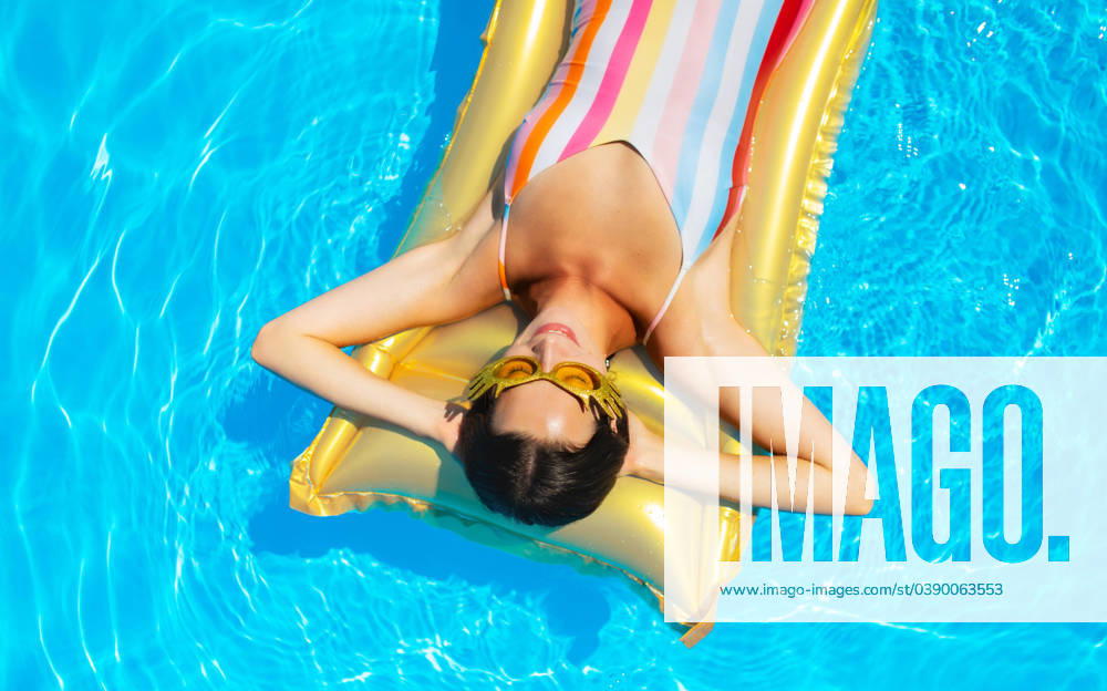 Top view of young woman in swimming pool outdoors on floating bed, relaxing. Top view of young woman with sunglasses in swimming pool outdoors on floating bed, relaxing. model released