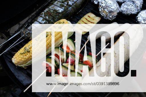 A high angle shot of seasoned vegetables on skewers, sausages, bread and stuffed fish cooking on grill 2386262