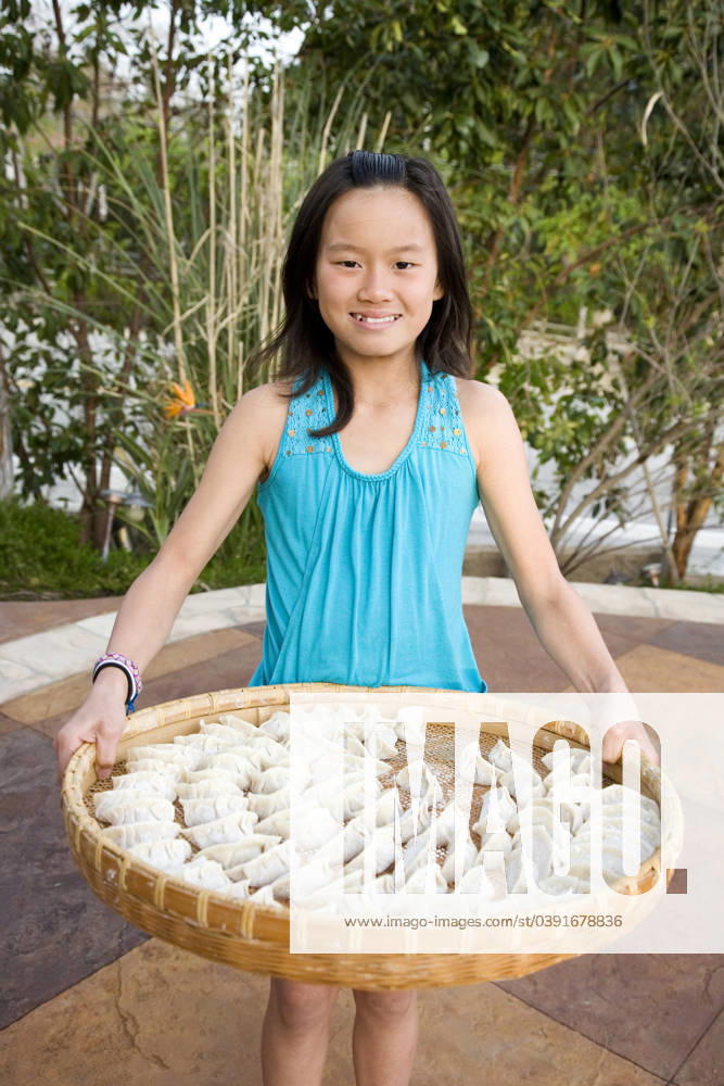 IMAGO Creative, Food, Dumplings Chinese girl holding basket of dumplings Alta Loma, California, United States, 21.12.2023, model released, TTBB_BLD088787.jpg, 8-9 years, asian ethnicity, black hair, childhood, chinese ethnicity, color image, day, domestic kitchen, domestic life, dumpling, elementary age, food and drink, front view, girl, girls, happy, healthy eating, healthy living, holding, lifestyle, looking at camera, one person, outdoors, patio, people, photography, portrait, posing, presenting, pride, smiling, standing, three quarter length, tradition, traditional culture, tray, vertical, minority, minoritiesasian, cheerful, child, children, color, colour, culture, custom, daylight, daytime, enjoyment, far eastern, female, food, gaiety, gal, glad, gleeful, human, hu