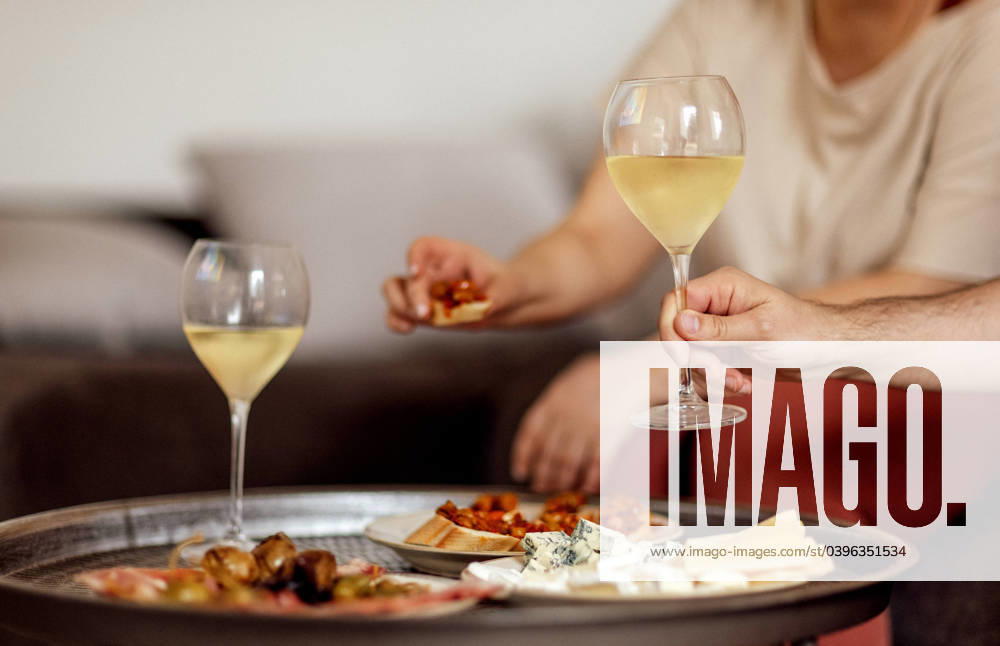 Two glasses of cool champagne and plates with various snacks on a round metal coffee table Two glasses of cool champagne and plates with various snacks on a round metal coffee table. White plates with slices of ham, salami, capers, olives and cheese. Cozy interior of the living room of the house. ,model released, Symbolfoto