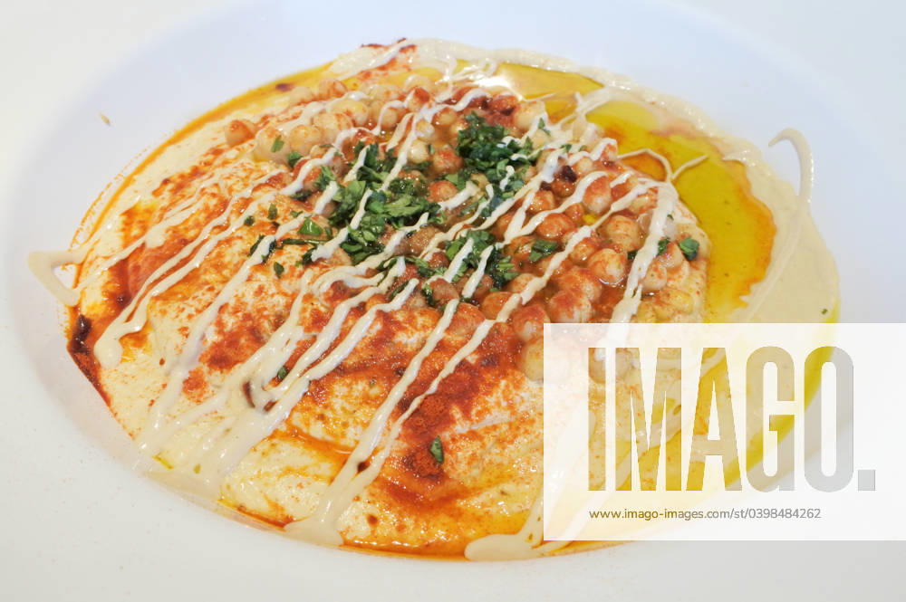 Hummus served in a plate Above view of Hummus served in a plate. Hummus is a Levantine dip or spread made from cooked, mashed chickpeas or other beans, blended with tahini, olive oil, lemon juice, salt and garlic.