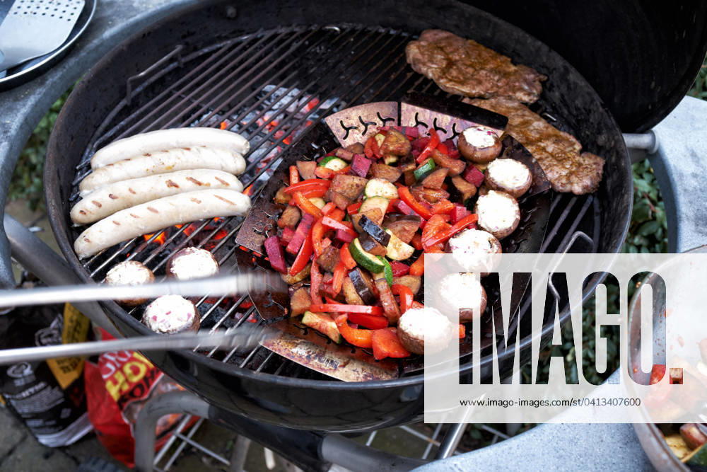 Barbecue at a Round grill become simultaneously Sausages, Steaks and Vegetables grilled Food NRW