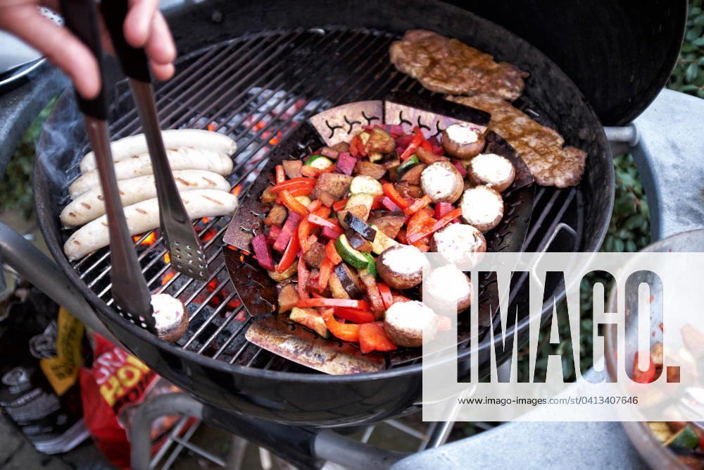 Barbecue at a Round grill become simultaneously Sausages, Steaks and Vegetables grilled Food NRW