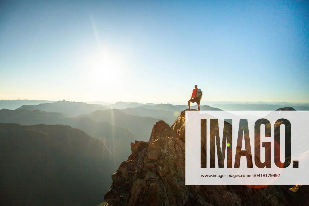 Successful hiker wearing backpack stands on mountain summit, sunset Glacier, Washington, United States CR_JDIP240227-1346412-01 ,model released, Symbolfoto