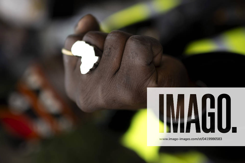 Gedenkmarsch Kolonialgeschichte DEU, Deutschland, Germany, Berlin, 25.02.2024 Demonstrant mit Faust und Ring in Form von Afrika als Symbol der African Black Community beim 17. Gedenkmarsch zur Erinnerung an die afrikanischen und schwarzen Opfer von Versklavung Kolonialismus und rassistischer Gewalt Maafa vom Komitee fuer die Errichtung fuer ein afrikanisches Denkmal Kadib in Berlin in Berlin Deutschland . Forderung nach Anerkennung der Verbrechen gegen Schwarze Menschen und Menschen afrikanischer Herkunft unter Einfluss der Black Lives Matter Bewegung. Mehr als 30 Millionen Afrikanerinnen und Afrikaner wurden Opfer von Versklavung und kolonialen Verbrechen. Die von Deutschland an den Herero und Nama begangenen Voelkermorde in Namibia und di