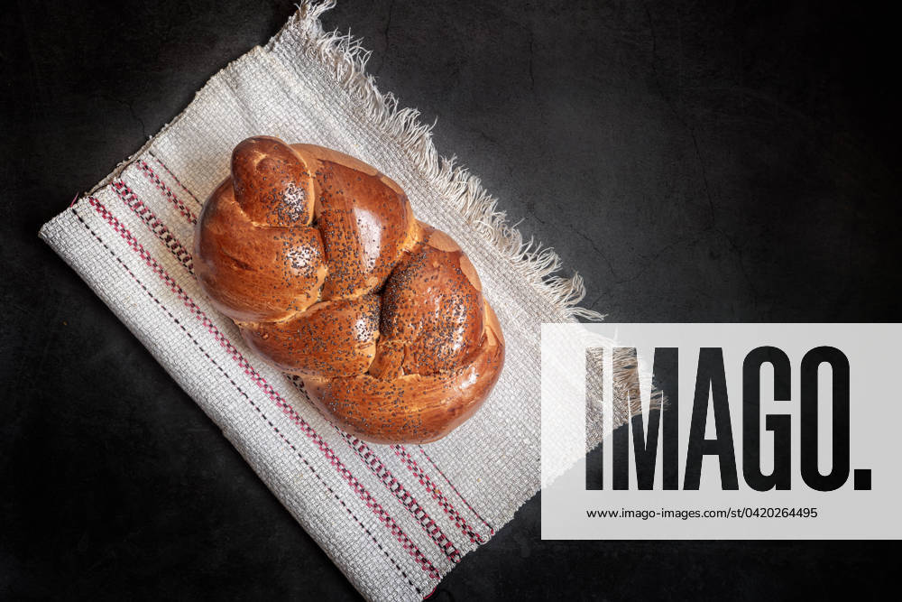 IMAGO Creative: Food, Mohn A loaf of white bread on a linen napkin On a linen napkin is a loaf of white bread in the shape of a plait with poppy seeds and a crisp crust. Presented on a dark background, top view, copy space