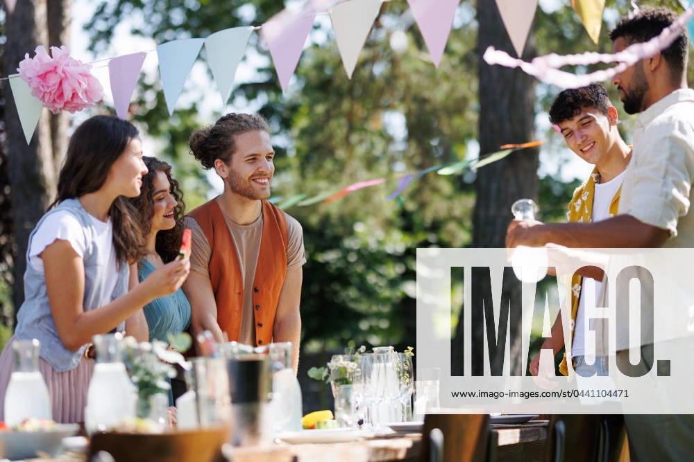 Friends and family talking and eating barbeque specialties at a summer grill garden party. Friends and family talking, having fun and eating barbeque specialties at a summer grill garden party. model released