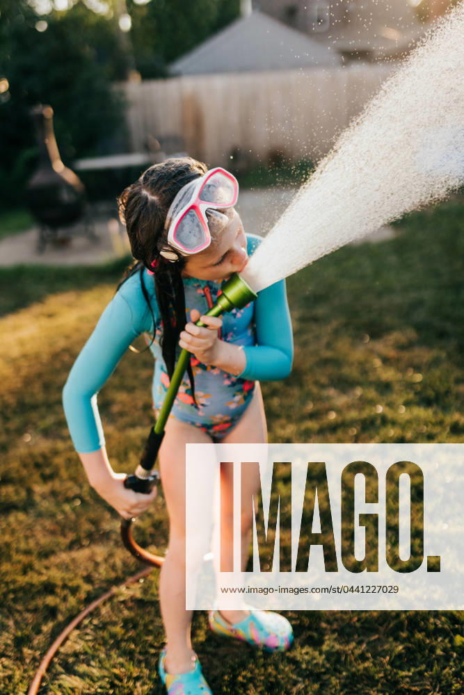 IMAGO Creative, Sommer, Sommertage im Garten IMAGO Creative, Jahreszeit Sommer, Sommerferien Close up of young girl in swimsuit drinks water from hose in backyard Sioux Falls, South Dakota, United States CR_ASWE240317-1369079-01 ,model released, Symbolfoto ,property released