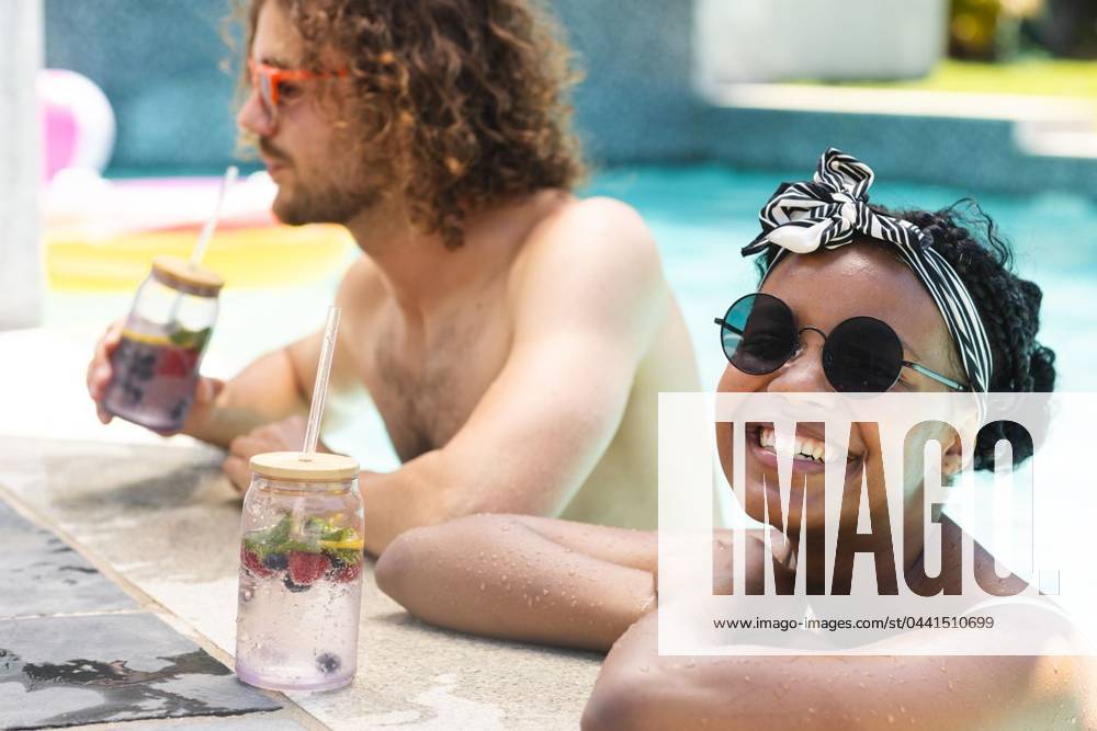 Diverse couple, a young African American woman and Caucasian man, relax by a pool, enjoying drinks Diverse couple, a young African American woman and Caucasian man, relax by a pool, enjoying drinks. She wears round sunglasses and a headscarf, while he sports curly hair and tinted glasses., model released, , property released, Cape Town, South Africa, 15.11.2023, 4961044.jpg, people,diverse couple,young African American woman,Caucasian man,pool,drinks,round sunglasses,headscarf,curly hair,tinted glasses,relaxation,leisure,fun,lifestyle,happy,relationship,love,summertime,outdoor,enjoyment,vacation,interracial,mixed race,diversity,cocktail,refreshment,chilling,lounging,leisure activity,poolside,holiday,romantic,bonding,sunbathing,swimwear,fas