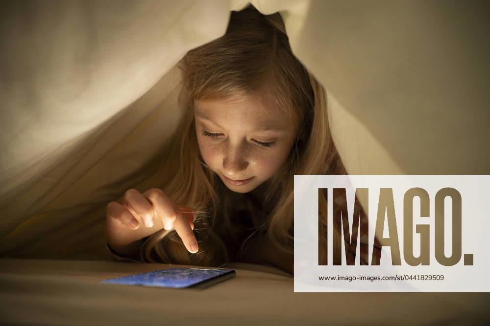 Girl using smart phone under blanket on bed at home model released, Symbolfoto property released, NJAF00878