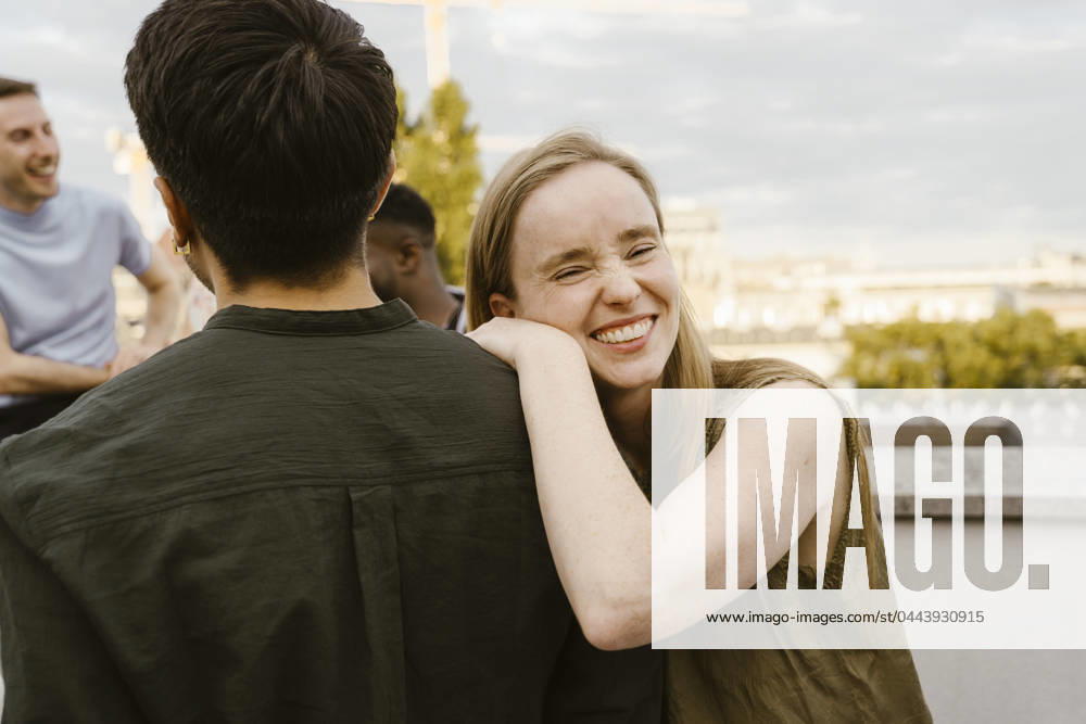 Portrait of smiling woman laughing while leaning on male friend s shoulder at party Germany, Berlin, model released, property released