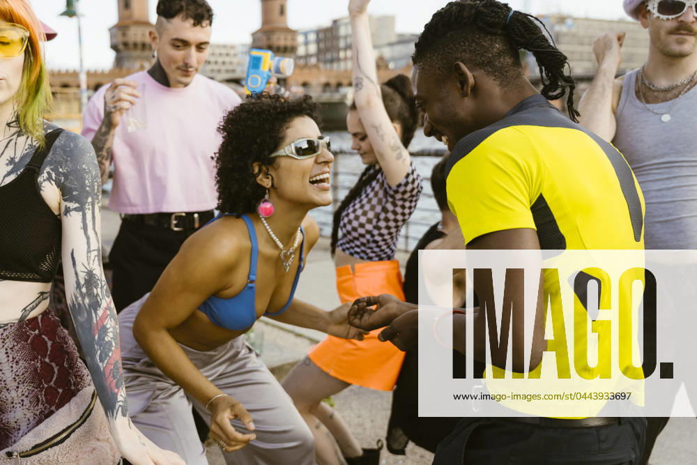 Happy non-binary person wearing sunglasses and dancing with friends in city Germany, Berlin, model released