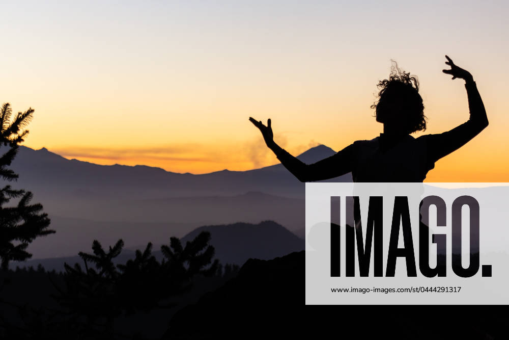 A dancer s silhouette is captured against the vibrant hues of a mountain sunset, reflecting a tranquil yet invigorating scene Model Released EduardoGavira_ID20613_608865_006