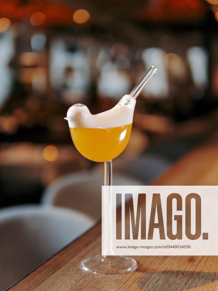 Yellow alcohol Tommy s Margarita cocktail Tommy s Margarita Cocktail in bird high stem cocktail glass. Yellow alcohol Tommy s Margarita cocktail on beautiful bar counter background with bokeh. Aesthetic yellow cocktail in bar interior