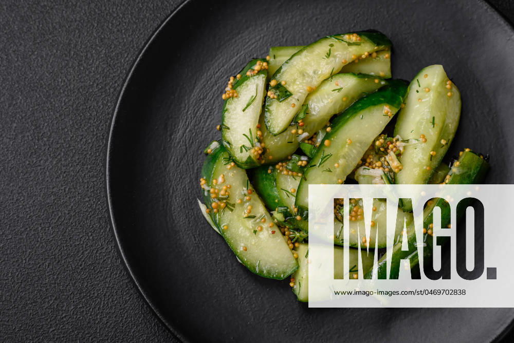 IMAGO Creative, Food, Gurkensalat Delicious juicy cucumber cut into large slices with salt, spices and french mustard Delicious juicy cucumber cut into large slices with salt, spices and french mustard on a dark concrete background