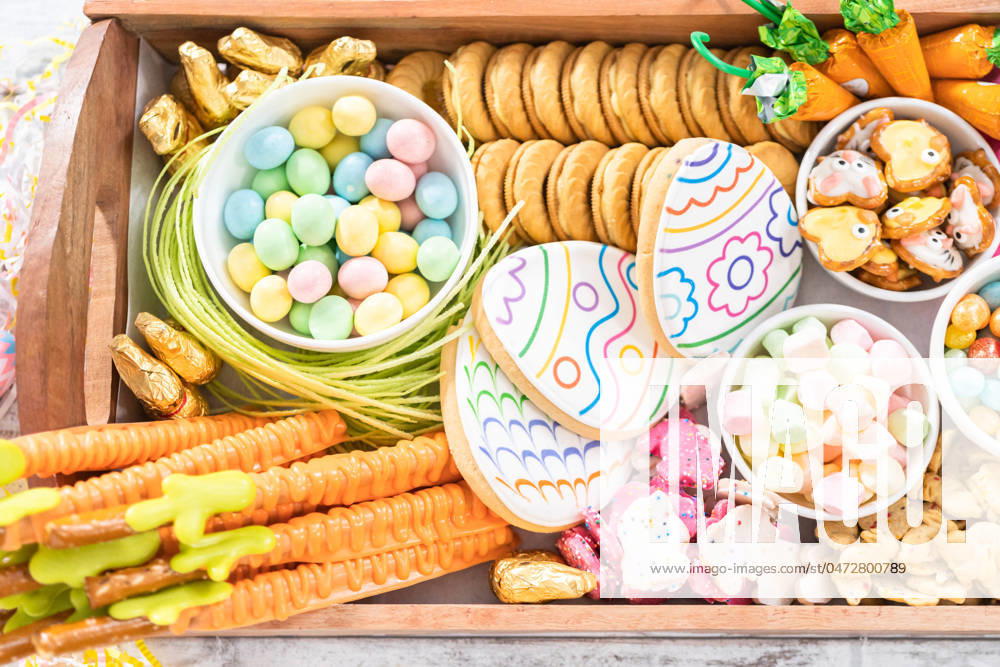Easter charcuterie board Assembling charcuterie board with Easter candies, cookies, and marshmallows.