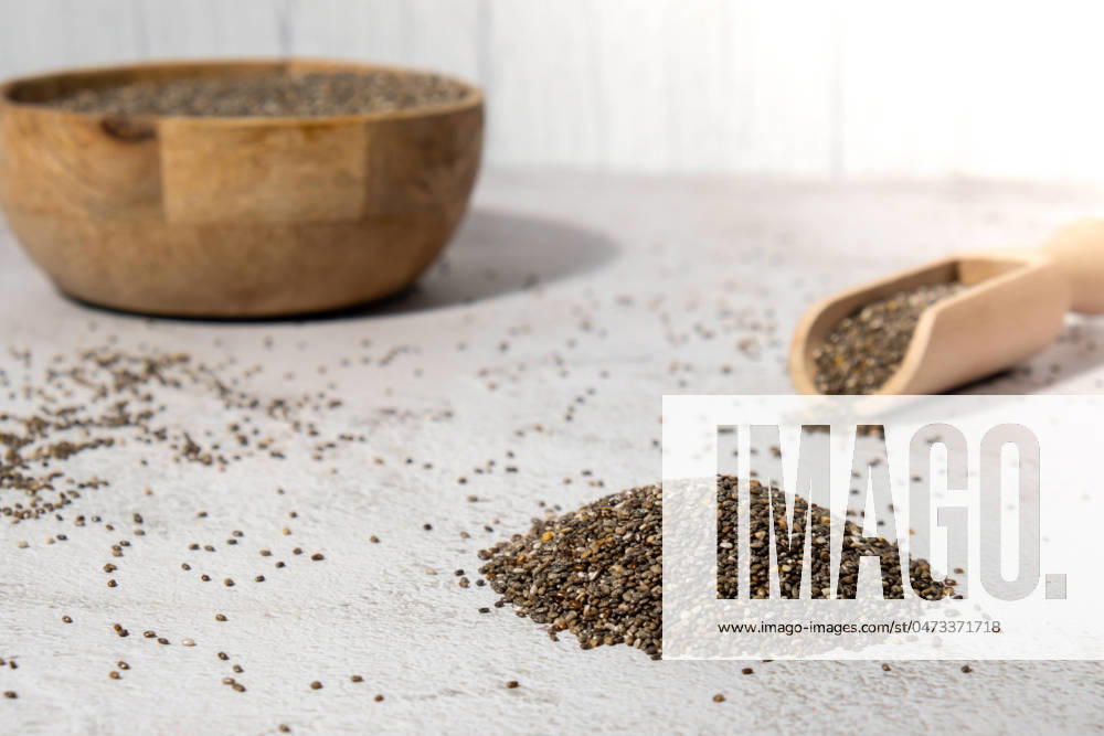 Heap of Chia seeds with wooden spoon. Healthy superfood rich in Omega 3 fatty acids. Dry healthy natural ingredient. Chia grains are falling Heap of Chia seeds with wooden spoon. Healthy superfood rich in Omega 3 fatty acids. Dry healthy natural ingredient. Chia grains are falling. Vegetarian food