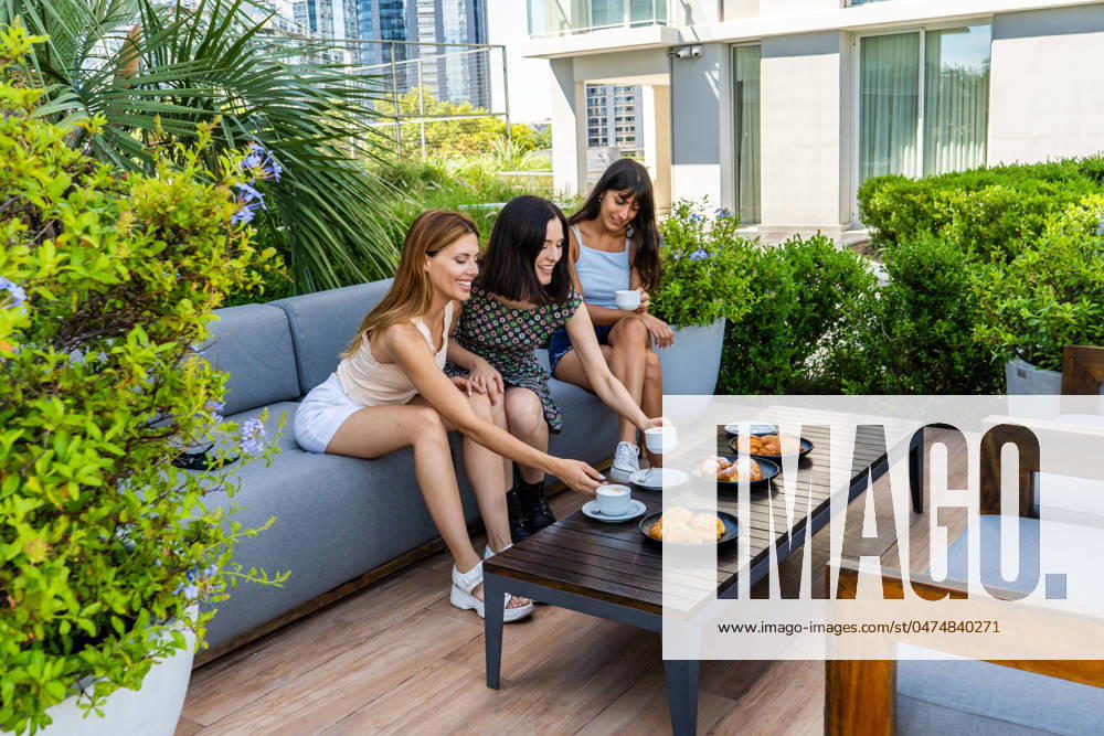 IMAGO Creative: Sommer, Sommertage im Garten Three friends sitting on a couch met to have breakfast outdoors. Model Released ValeriaVenezia_ID20536_606556_045