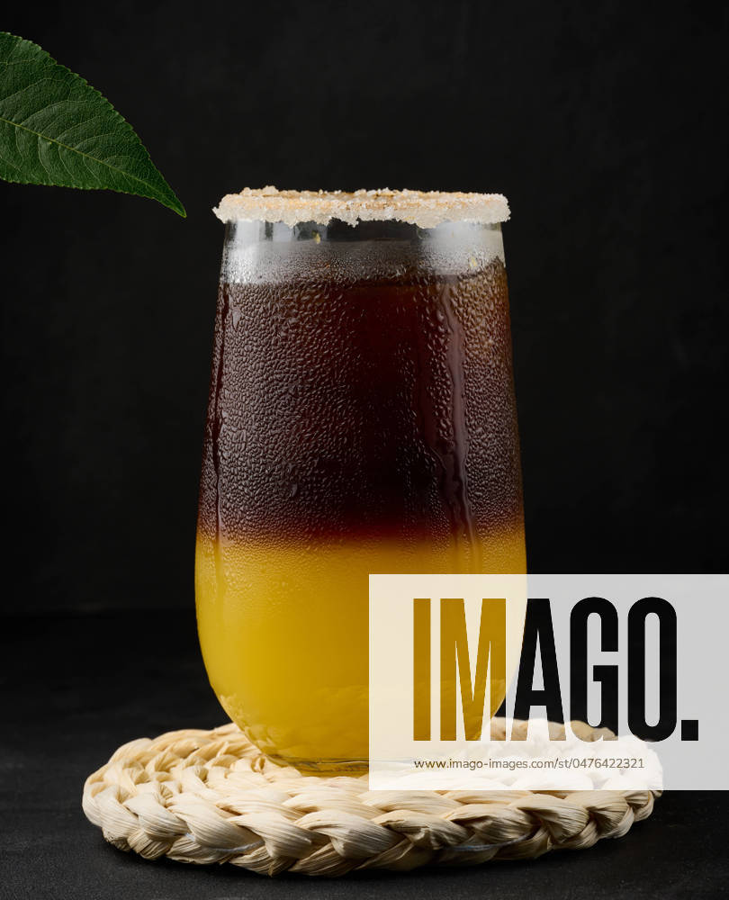 Iced coffee with orange juice in a transparent glass, refreshing bumble coffee on the table, black background